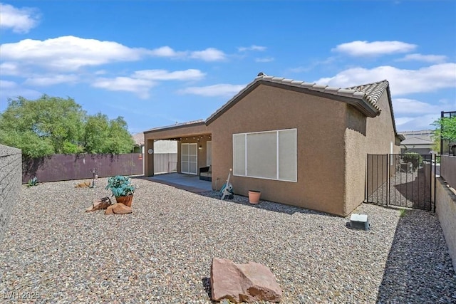back of property featuring stucco siding, a tile roof, a patio, and a fenced backyard