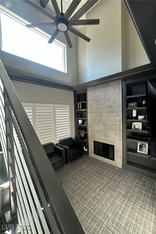 2715 Twin Palms Cir, Las Vegas, NV 89117 - living room with ceiling fan, a high ceiling, a tile fireplace, built in shelves, and stairway