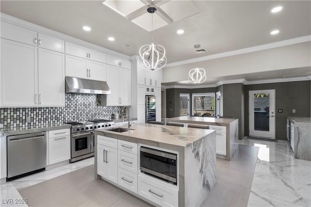 2715 Twin Palms Cir, Las Vegas, NV 89117 - kitchen with appliances with stainless steel finishes, under cabinet range hood, a kitchen island with sink, ornamental molding, and a chandelier
