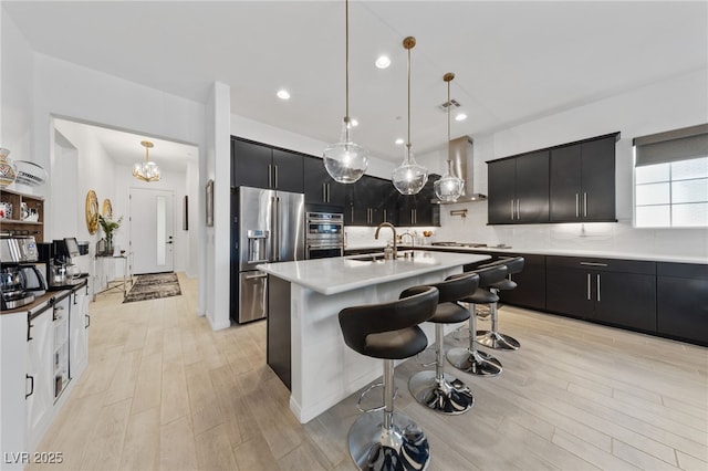 12 Tatahatso Point St, Henderson, NV 89011 - kitchen with stainless steel appliances, a sink, dark cabinetry, wall chimney exhaust hood, and recessed lighting