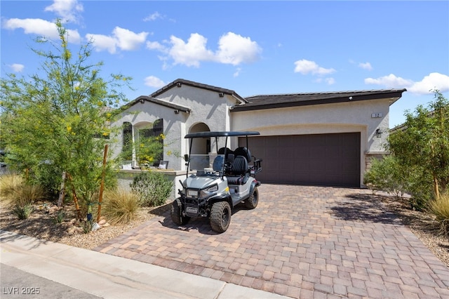 view of front facade with a garage, stucco siding, and decorative driveway