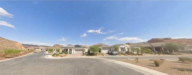view of road with a residential view, a mountain view, and curbs