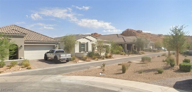 view of front of house featuring decorative driveway, a garage, stucco siding, and a tiled roof