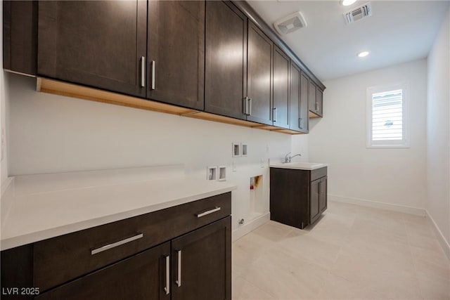 washroom with a sink, cabinet space, baseboards, visible vents, and washer hookup