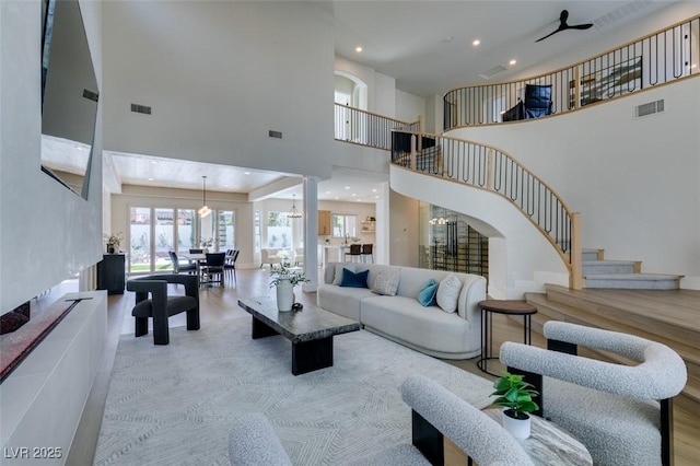 living room with recessed lighting, stairway, visible vents, and a towering ceiling