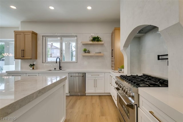 kitchen with recessed lighting, a sink, light wood-style floors, decorative backsplash, and appliances with stainless steel finishes