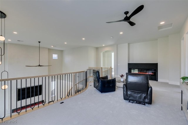 sitting room with arched walkways, recessed lighting, carpet, an upstairs landing, and ceiling fan