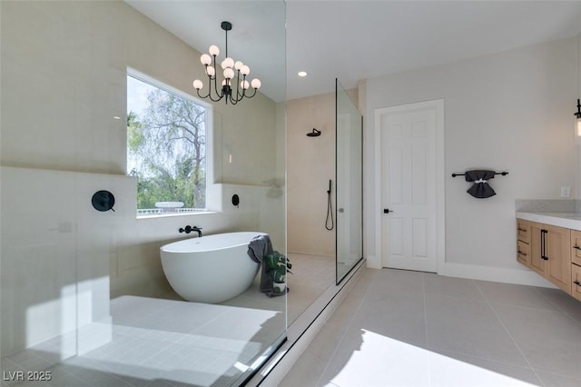 full bath featuring tile patterned floors, an inviting chandelier, vanity, a soaking tub, and a stall shower
