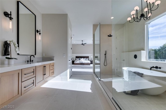 ensuite bathroom featuring ceiling fan with notable chandelier, tile patterned flooring, vanity, and a walk in shower