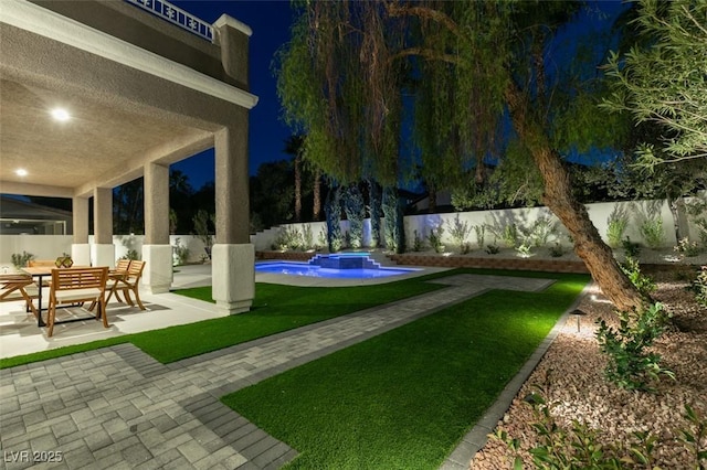 yard at night with a patio area, a fenced backyard, a fenced in pool, and a jacuzzi