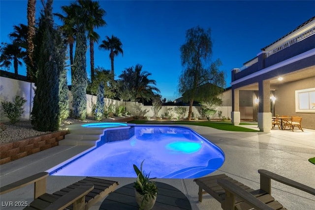 pool at night with a fenced backyard, a fenced in pool, an in ground hot tub, and a patio