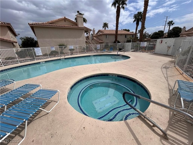 community pool featuring fence, a hot tub, and a patio