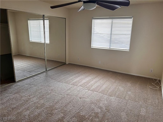 unfurnished bedroom featuring carpet floors, a closet, baseboards, and a ceiling fan