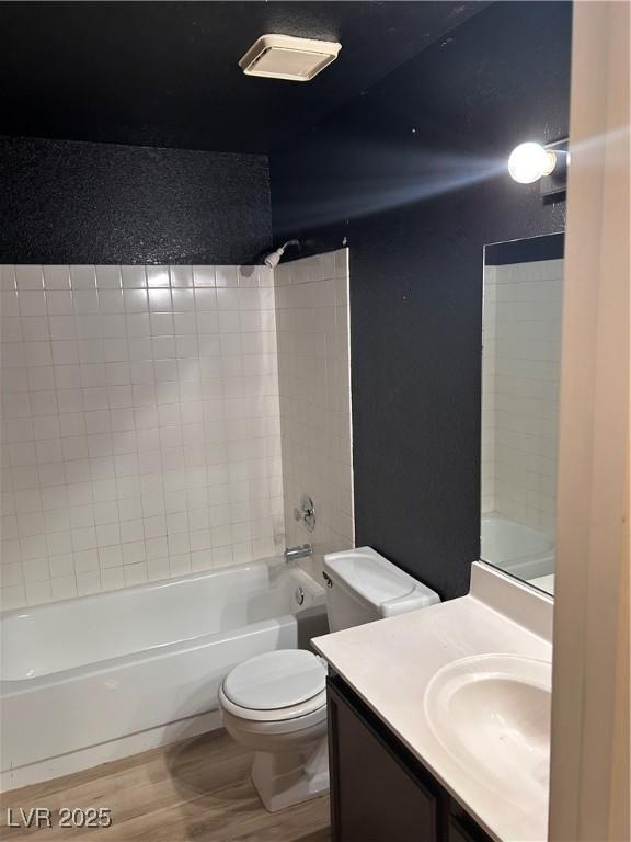 bathroom with wood finished floors, toilet, vanity, and shower / bath combination