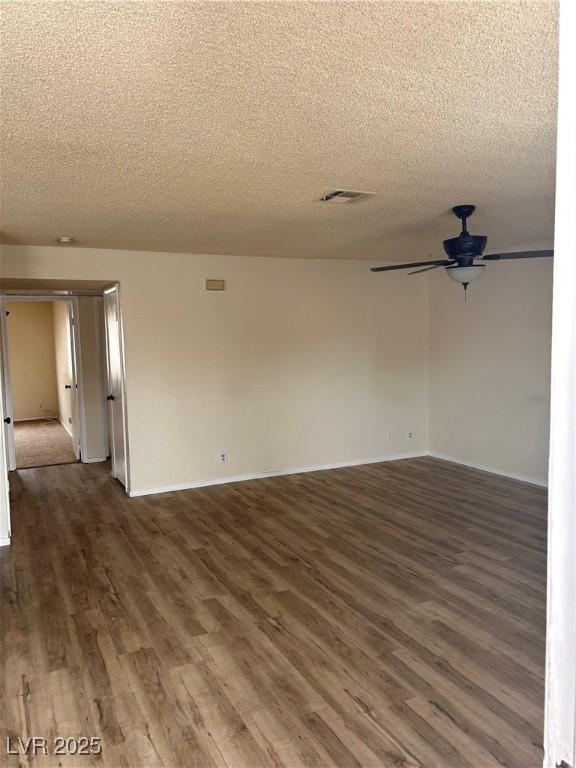 spare room with a textured ceiling, wood finished floors, a ceiling fan, and baseboards