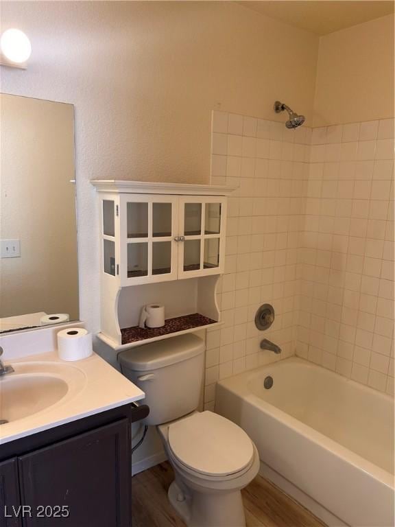 bathroom featuring toilet, vanity, tub / shower combination, and wood finished floors