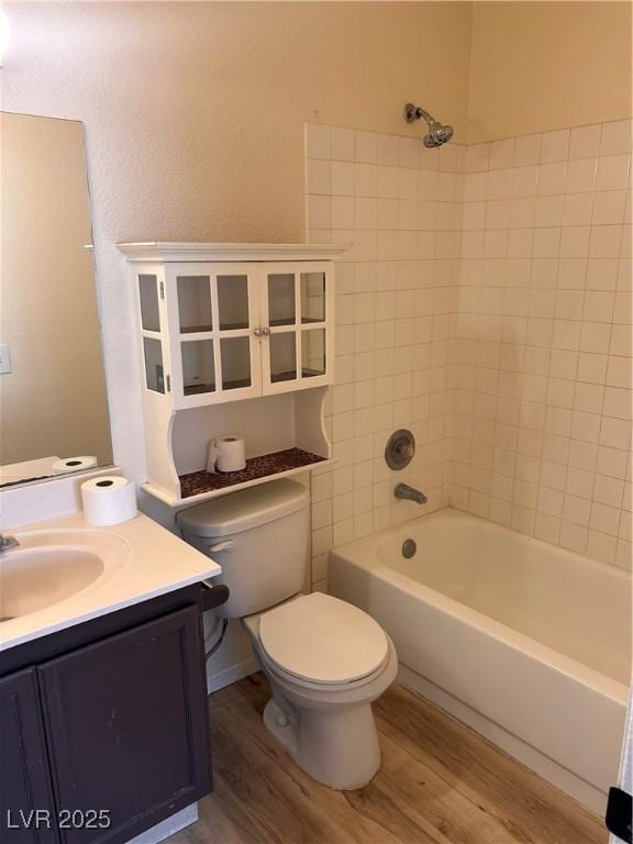 full bath with wood finished floors, toilet, vanity, and washtub / shower combination