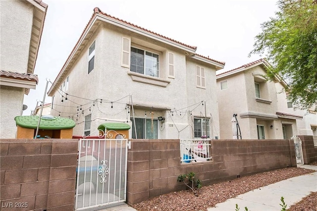 view of front of house featuring a gate, a fenced front yard, a tile roof, and stucco siding