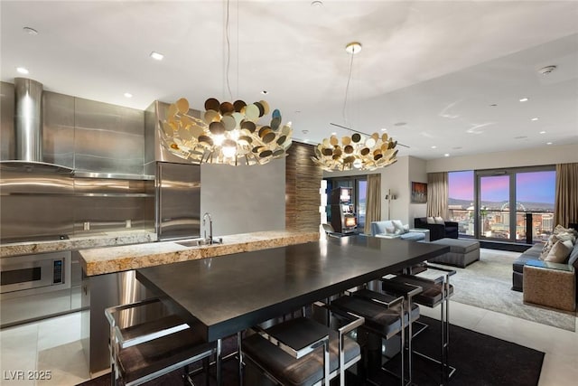 kitchen with light stone countertops, a sink, stainless steel microwave, and light tile patterned floors