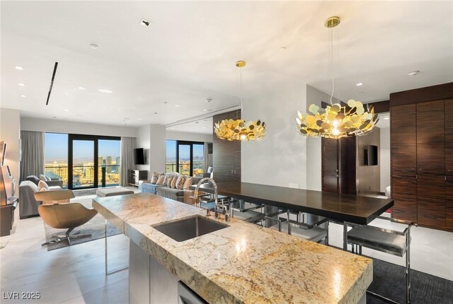 kitchen with a sink, an island with sink, modern cabinets, pendant lighting, and recessed lighting