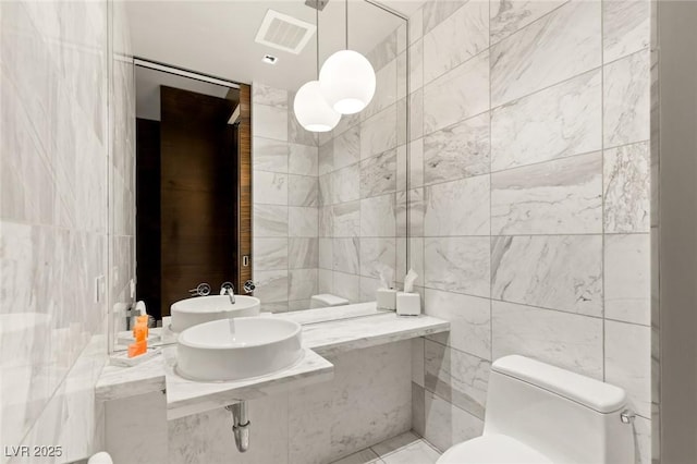 bathroom with tile patterned flooring, tile walls, visible vents, and toilet
