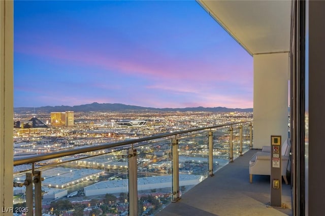 balcony at dusk featuring a city view and a mountain view