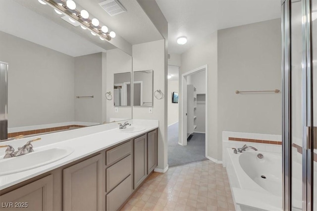 bathroom featuring a garden tub, visible vents, a sink, and double vanity
