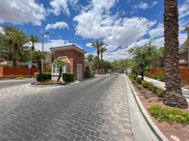 view of road featuring a gated entry, curbs, and street lights