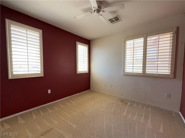 carpeted spare room featuring a ceiling fan, baseboards, and visible vents