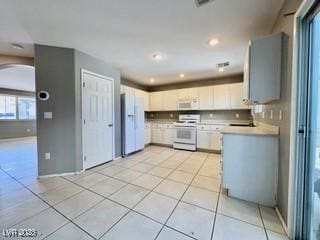 kitchen with light tile patterned floors, white appliances, arched walkways, light countertops, and white cabinets