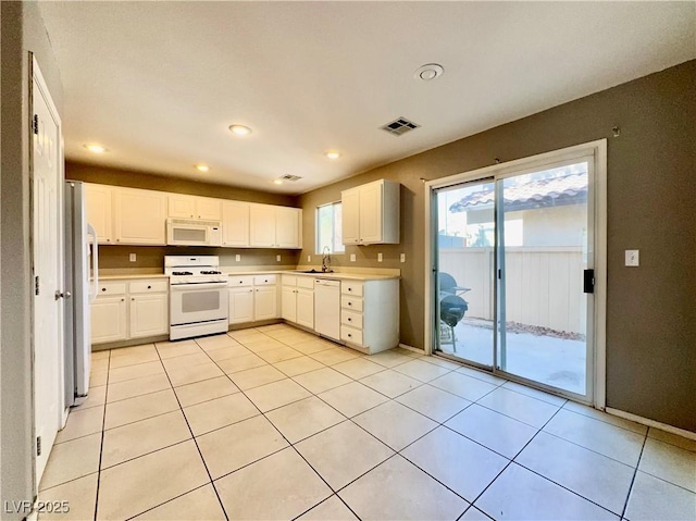kitchen with white appliances, visible vents, a sink, white cabinetry, and light countertops
