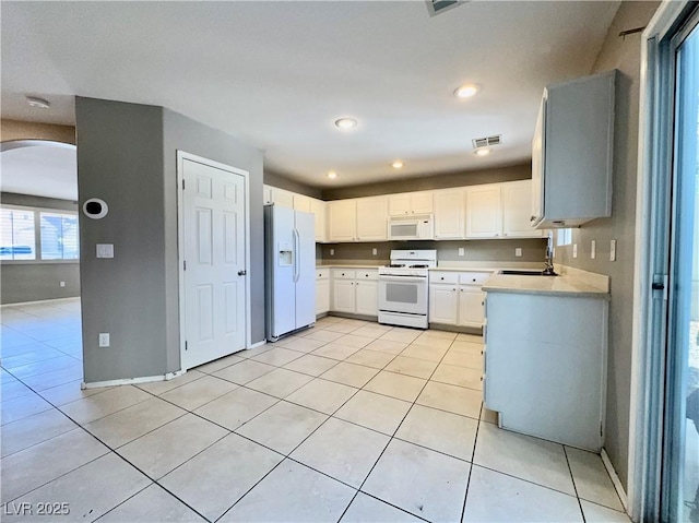 7173 Dravite Ct, Las Vegas, NV 89148 - kitchen featuring white appliances, arched walkways, a sink, light countertops, and light tile patterned floors