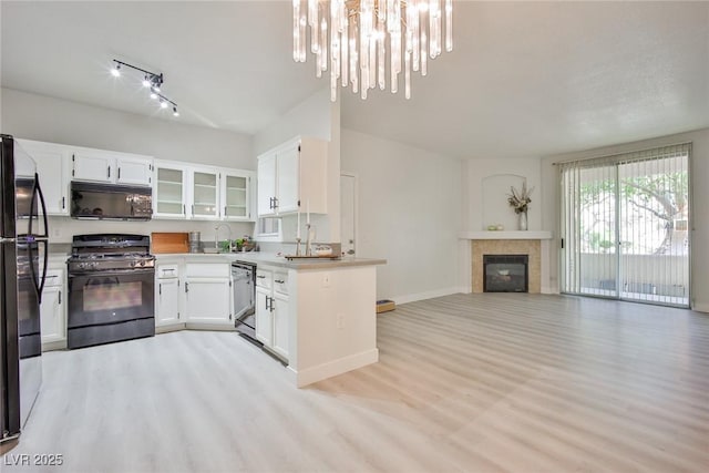 kitchen featuring white cabinets, light wood-style floors, open floor plan, and black appliances