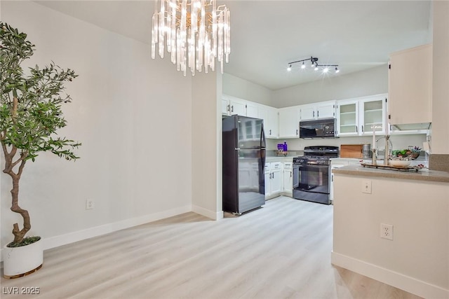 kitchen featuring light wood finished floors, baseboards, and black appliances