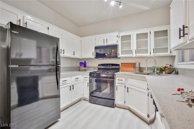 kitchen with white cabinets, glass insert cabinets, a sink, and black appliances