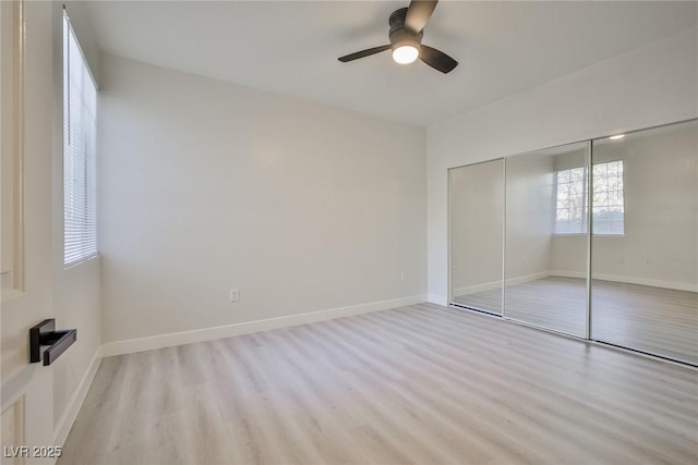unfurnished bedroom with light wood-style floors, a closet, a ceiling fan, and baseboards
