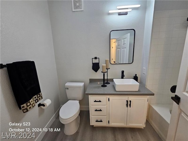 bathroom featuring toilet, vanity, wood finished floors, and shower / bathing tub combination