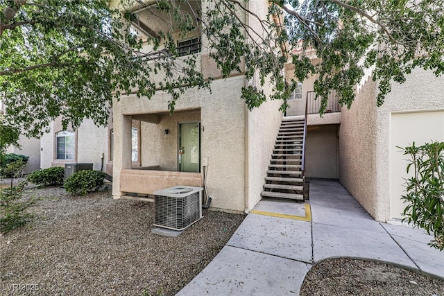 view of exterior entry with stucco siding and central AC unit