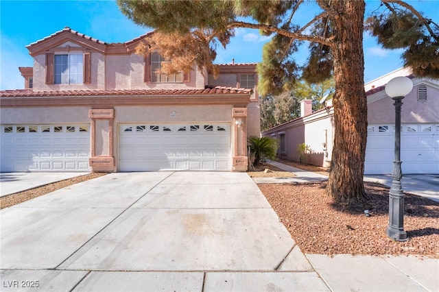 view of front of home featuring stucco siding, an attached garage, driveway, and a tiled roof
