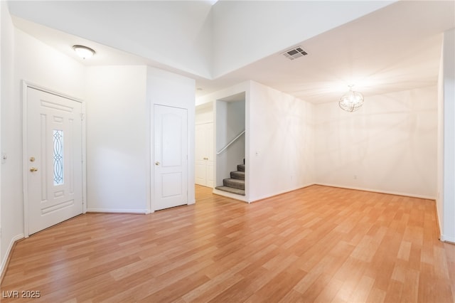 foyer with stairs, light wood-style floors, an inviting chandelier, baseboards, and visible vents