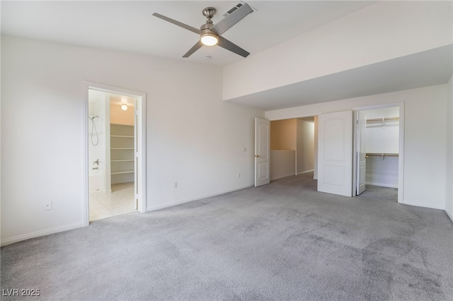 unfurnished bedroom with carpet flooring, ensuite bathroom, baseboards, a spacious closet, and ceiling fan