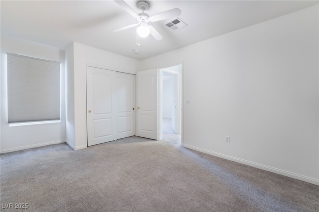 unfurnished bedroom featuring light colored carpet, baseboards, visible vents, and a closet
