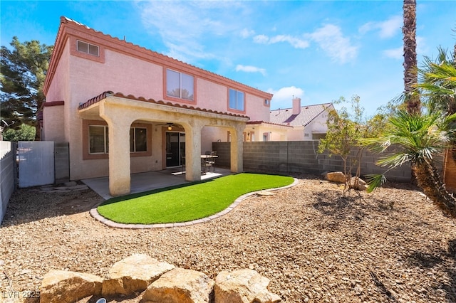 back of house with a ceiling fan, a tiled roof, a fenced backyard, and stucco siding
