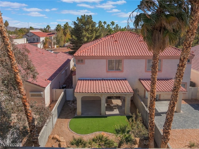 rear view of house featuring a patio area, a tiled roof, a fenced backyard, and stucco siding