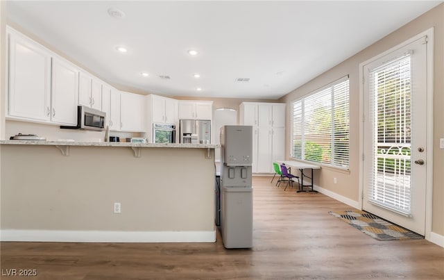 kitchen featuring a breakfast bar area, white cabinetry, baseboards, appliances with stainless steel finishes, and recessed lighting