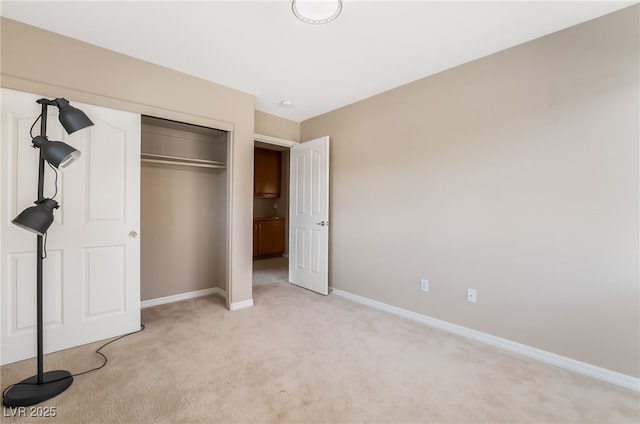 unfurnished bedroom with baseboards, a closet, and light colored carpet