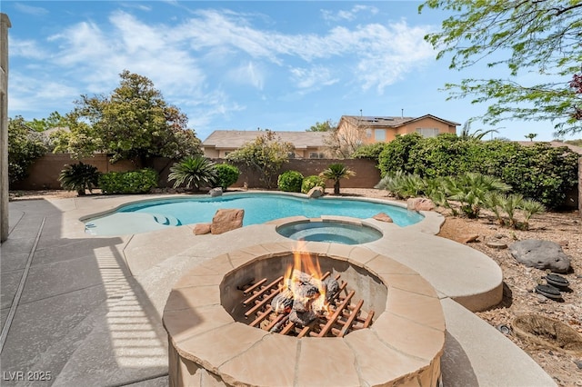 view of pool featuring a pool with connected hot tub, a patio, a fenced backyard, and an outdoor fire pit
