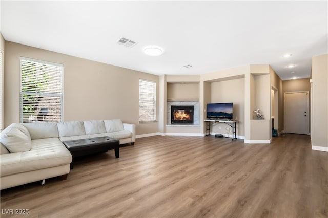 living room with light wood-type flooring, a fireplace, baseboards, visible vents, and recessed lighting