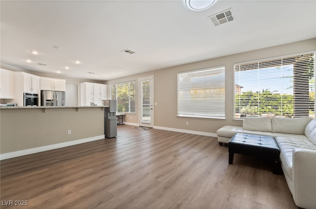 living room featuring baseboards, light wood-style floors, visible vents, and recessed lighting