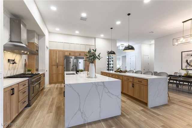 1350 Rossini St, Henderson, NV 89052 - kitchen featuring premium appliances, wall chimney exhaust hood, a large island with sink, a sink, and light wood-style flooring